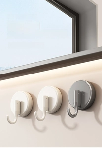 Close-up of vacuum suction hooks in pearl white and metallic grey on a bathroom wall