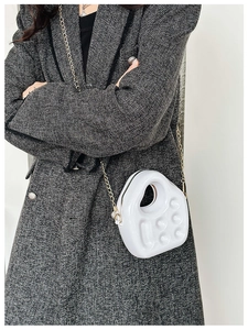 Detailed view of a white PVC jelly mini handbag with chain strap on a grey coat
