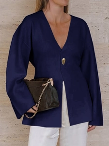 Close-up of navy blue long sleeve knit cardigan featuring a single gold irregular button