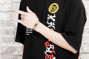 Close-up of men's braided black leather bracelet featuring a golden H-shaped clasp