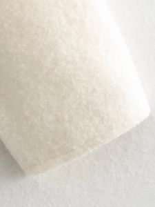 Macro shot showing soft white wool texture and plush fabric detail of the short jacket