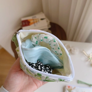 Detail of floral cotton mini pouch storing three colorful scrunchies inside