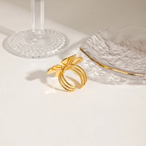 Detail of a golden butterfly ring with triple layered bands on a textured glass plate