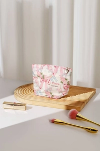 Detail of floral makeup bag with pink bow pattern and golden petal zipper pull
