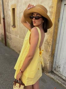 Detail of yellow backless summer set with bow tie and matching skirt on sunny street
