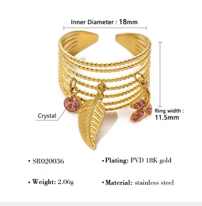 Macro detail of gold-plated multi-layer ring with leaf and pink crystal charms