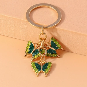 Detailed macro view of a gold keychain with three green and yellow butterfly pendants
