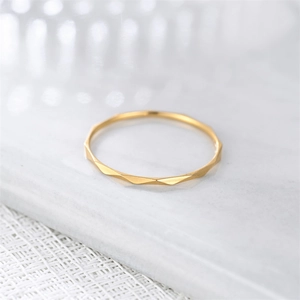 Detailed macro shot of a 1mm geometric faceted gold ring on a white marble surface.