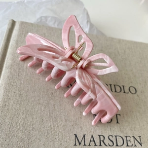 Detailed close-up of a pink marble butterfly hair claw clip with golden metal spring