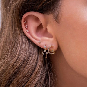 Macro shot of celestial ear studs set with moon and star pendants in gold plating