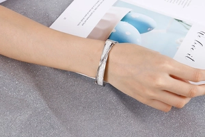 Detail of silver crisscross bangle with crystal embellishments on a stylish magazine