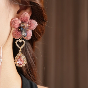 Détail de boucles d'oreilles fleur brodée rose avec gouttes en cristal et cœurs