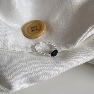 Detail of a 925 sterling silver open ring with an oval black onyx on white linen fabric