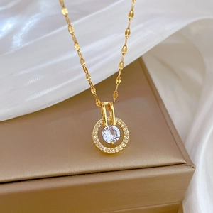 Primo piano di una collana d'oro con pendente circolare in zircone su una scatola regalo