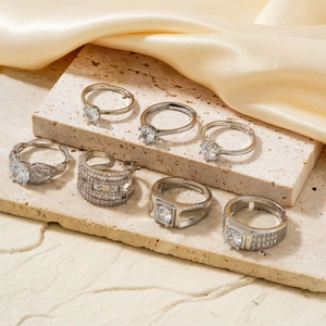 Set of seven silver-colored open rings with zircon stones on stone and silk background