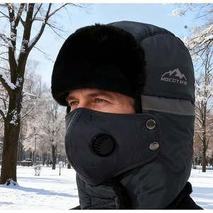 Gros plan d'un chapeau de trappeur d'hiver avec masque à valve respiratoire dans la neige