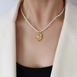 Close-up of pearl necklace with a 18k gold-plated irregular oval cameo pendant on a model