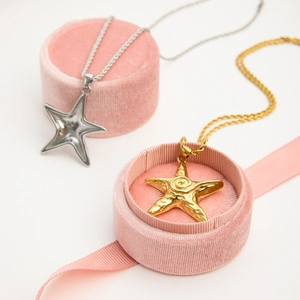 Detailed view of gold and silver starfish necklaces on elegant pink velvet jewelry cases