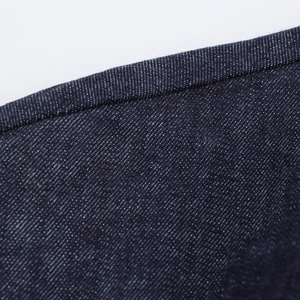 Gros plan du tissu denim bleu foncé avec texture sergé et détails de couture précis