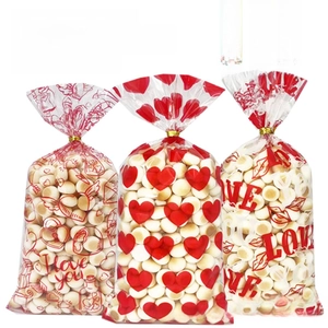 Detailed view of printed OPP candy bags with red heart patterns and gold twist ties