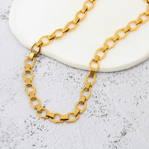 Macro detail of golden chunky chain necklace with Greek key pattern and hexagonal links