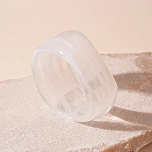 Macro view of white acrylic wide band ring with marble swirl on textured stone