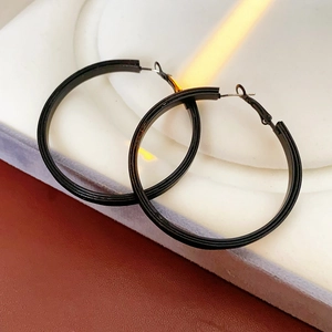 Gros plan de boucles d'oreilles créoles en cuir noir mat sur un support d'exposition