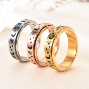 Detail of three rotating metal rings in silver, rose gold, and gold with cosmic patterns