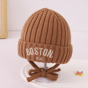 Detail of a brown ribbed knit baby hat featuring white BOSTON 1630 embroidery and a tie bow