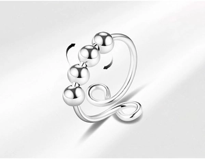 Detail of silver spinning beads on a clip-on anxiety ring showing rotation function