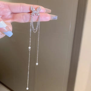 Detail of silver tassel earrings with butterfly design and delicate rhinestone chains