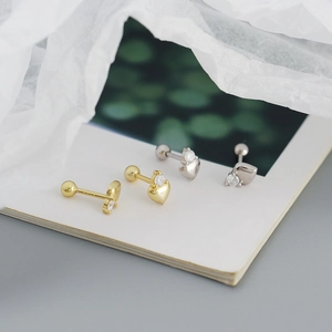 Close-up of gold and silver heart-shaped screw-back earrings with diamonds on a book