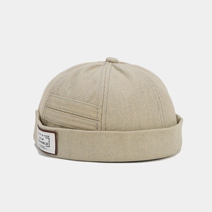 Detailed side view of a beige denim docker hat featuring a stylish vintage letter patch