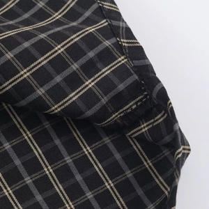 Detailed close-up of woven fabric showing black, gray, and beige plaid pattern
