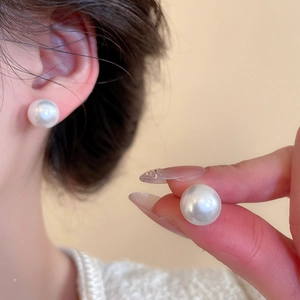 Macro shot of a model wearing a premium round white pearl stud earring with high luster
