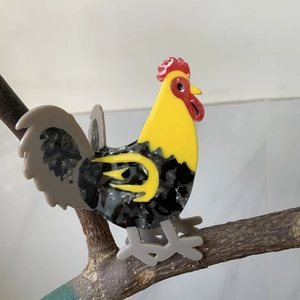 Cartoon rooster cellulose acetate hair claw clip displayed on a natural tree branch
