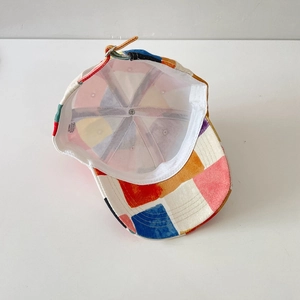 Detail of adjustable metal buckle and leather strap on multi-colored patchwork cap