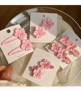 Close-up of pink cherry blossom hair clips on display card with soft sunlight shadows