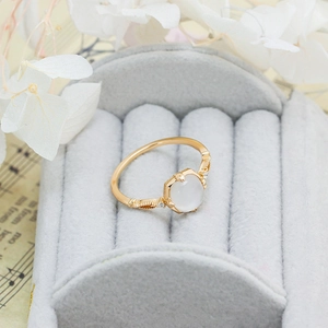 Macro shot of gold S925 ring with white gemstone in a soft gray velvet jewelry box