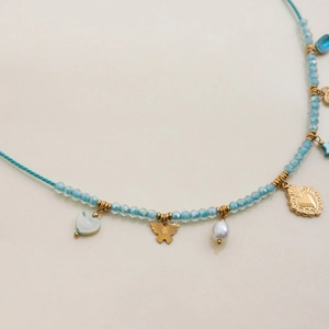Close-up of light blue beaded necklace with gold butterfly, heart shell and pearl charms