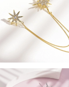 Detail of gold starburst ear cuff with clear zircon stones and thin metal chains