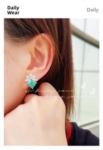 Detail of emerald green square stud earrings with crystal cluster on a golden setting