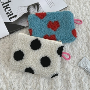 Detail of plush lamb wool heart and polka dot patterns on mini cosmetic storage bags