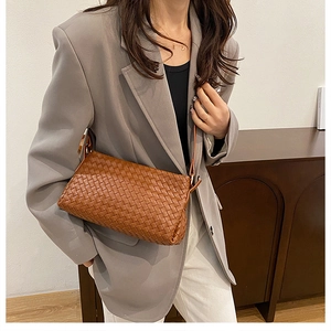 Détail de la texture en cuir tissé main marron sur un sac à bandoulière minimaliste