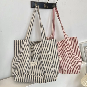 Detailed view of large canvas tote bags with navy and red stripes hanging on wooden hooks