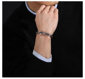 Close-up of a men's Thai silver braided bangle with hammered texture on a model's wrist