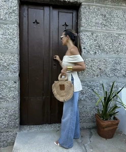 Detail of a straw tote bag with fringe tassels and a semi-circular woven design