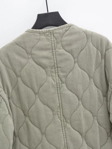 Détail de la texture matelassée en vagues et de l'encolure sur la veste verte