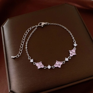 Detail of silver clover bracelet with pink gemstones on a dark luxury jewelry box