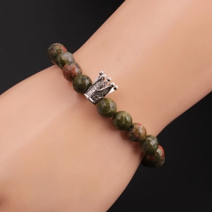 Detail view of 8mm Unakite stone bead bracelet with a silver crown pendant on wrist